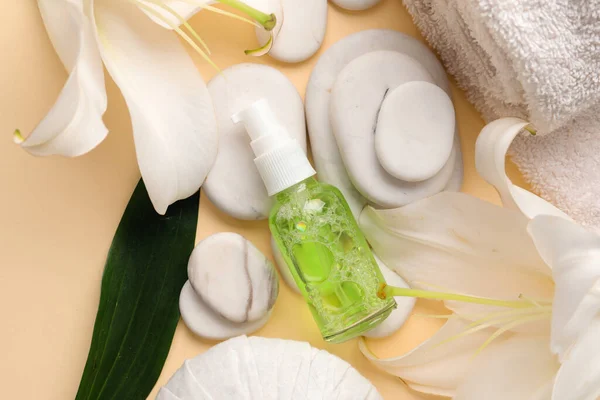 Composition with bottle of cosmetic product, spa accessories and lily flowers on color background