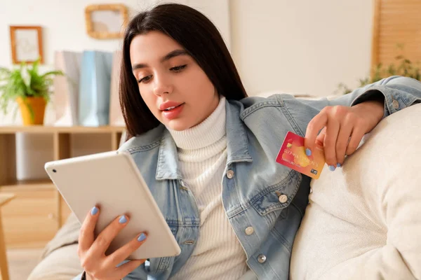 Young woman with tablet computer and credit card shopping online at home, closeup
