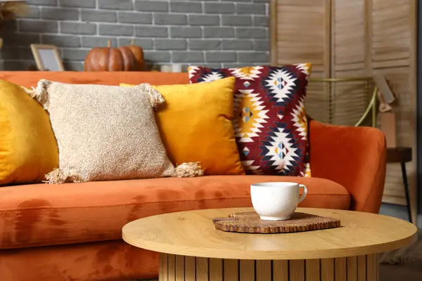 Interior of stylish living room with orange sofa, cushions and wooden coffee table, closeup