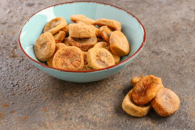 Koyu arkaplanda kurutulmuş incir kâsesi.