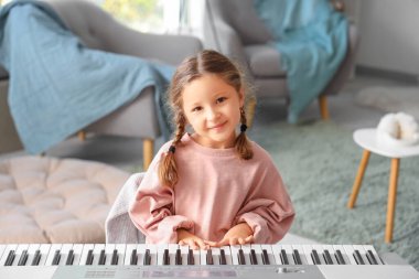 Evde sentezleyici oynayan sevimli küçük kız.