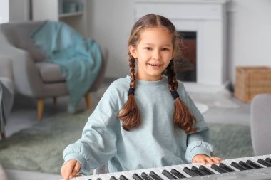 Evde sentezleyici oynayan sevimli küçük kız.