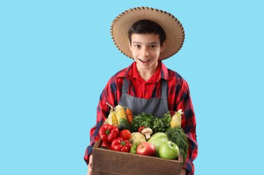 Mavi arka planda taze yiyeceği olan küçük çiftçi.