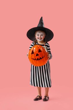 Cadılar Bayramı için giyinmiş şirin küçük kız pembe arka planda balkabağı olan cadı.