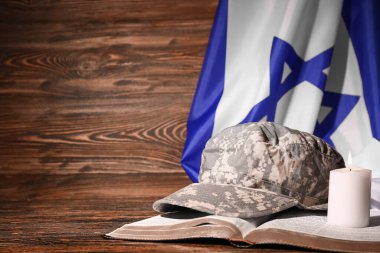 Tevrat askeri şapkalı, yanan mum ve tahta masada İsrail bayrağı.