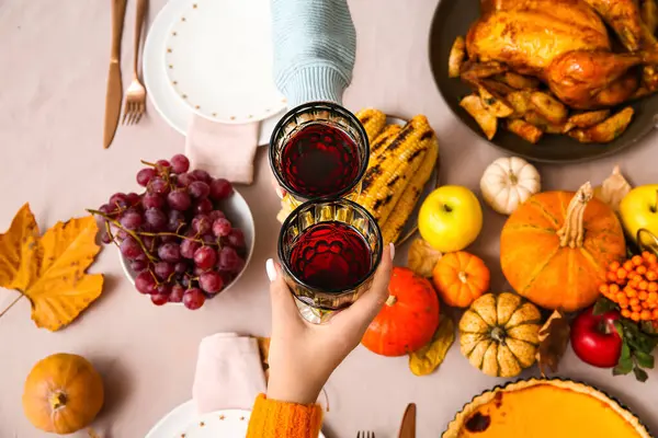 Woman with wine and tasty food on dining table set for Thanksgiving Day, top view
