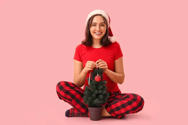 Gyönyörű Fiatal Pizsama Mikulás Kalap Díszítő Karácsonyfa Rózsaszín Háttér — Stock Fotó