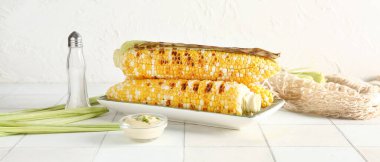 Lezzetli ızgara mısır koçanı, beyaz masada tuz ve sos.