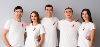 Gri arka planda kırmızı kurdeleli bir grup insan. Dünya AIDS Günü