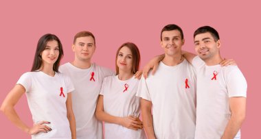Pembe arka planda kırmızı kurdeleli bir grup insan. Dünya AIDS Günü