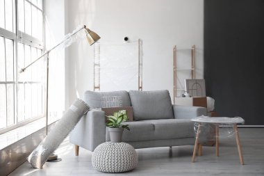 Taşındığı gün oturma odasında esnek ambalajlı ve mobilyalı karton kutular.