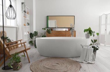 Lavabosu, küveti, raf ünitesi ve çiçekleri olan hafif banyonun içi.