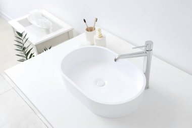 Banyodaki beyaz lavabo ve banyo aksesuarları, yakın plan.