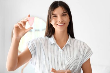 Yatak odasında regl fincanı olan genç bir kadın.