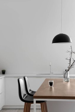 Modern mutfaktaki bir adada ağaç dalları ve bir bardak kahve olan vazo.