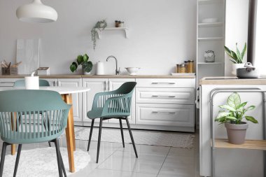 Mutfağın içinde yemek masası ve beyaz tezgahlar var.