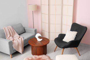 Koltuklar ahşap sehpa, puf ve tuvalet perdesi pembe duvarın yanında.