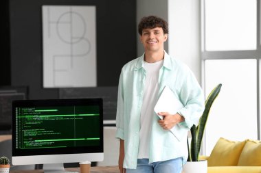 Ofiste çalışan dizüstü bilgisayarı olan erkek programcı.