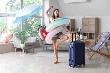 Yüzme yüzükleri ve bavulu olan genç kadın yaz tatiline evde hazır.