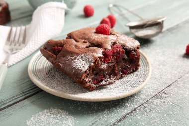 Mavi ahşap masanın üzerinde bir parça ahudududulu çikolatalı brownie.