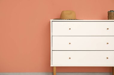 Renkli duvarın yanındaki çekmecelerin üstündeki hasır şapka