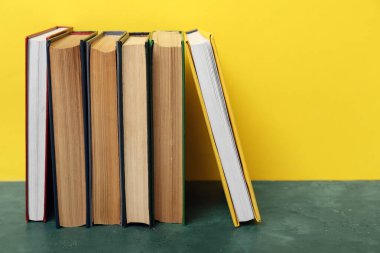 Sarı arkaplana karşı yeşil masadaki kitaplar