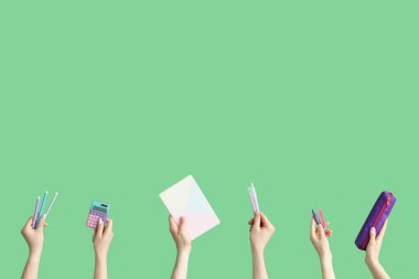 Hands with school accessories on green background