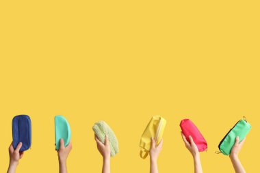 Sarı arka planda kalem kılıflı eller