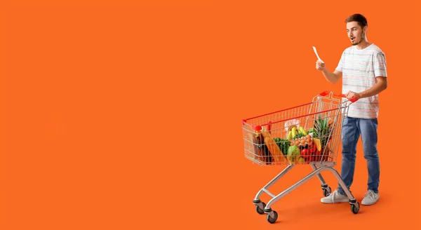Man with list of products and shopping cart on orange background with space for text