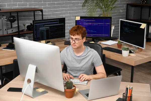 Male programmer working with computer at table in office