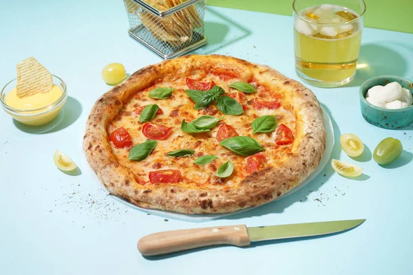 Tasty pizza Margarita with basil and glass of beer on blue table