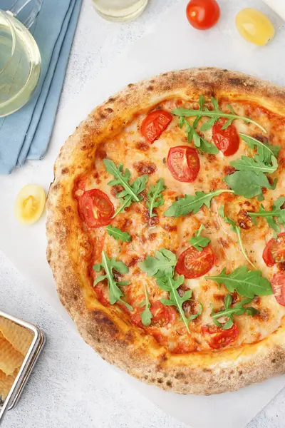 Tasty pizza Margarita with tomatoes and arugula on light blue table
