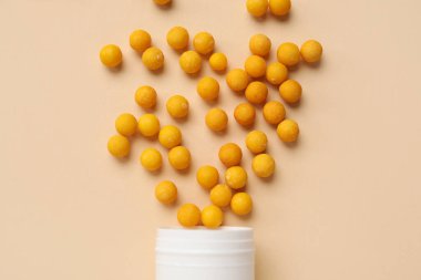 Turuncu arka planda dağınık haplarla dolu kavanoz.