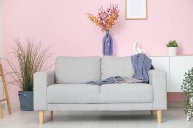 Gri kanepesi, çiçekleri ve çiçekleri olan şık bir oturma odası.