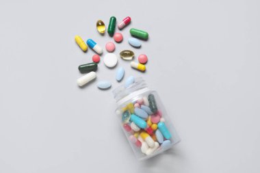 Gri arka planda farklı dağılmış haplarla dolu kavanoz.