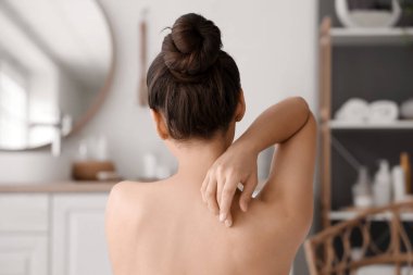 Genç bir kadın evde banyo yapıyor, arkadan bakıyor.