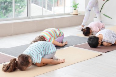 Beden eğitimi hocasıyla yoga yapan bir grup çocuk.