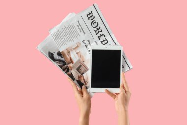 Boş tablet bilgisayarı ve pembe arka planda gazetesi olan kadın.