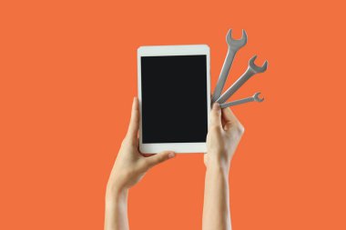 Boş tablet bilgisayarı ve turuncu arka planda anahtarı olan bir kadın.