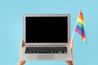 Mavi arkaplanda LGBT bayrağı ve boş dizüstü bilgisayarı olan kadın