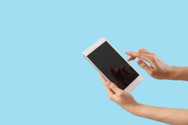 Mavi arkaplanda boş tablet bilgisayarı olan kadın