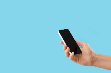 Mavi arka planda boş cep telefonu olan kadın