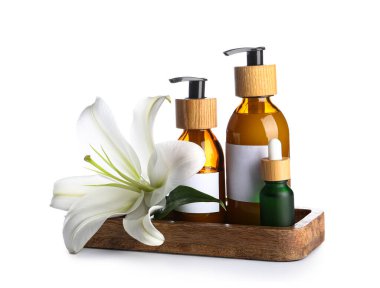 Tahta tahta tahta tahta, beyaz arka planda kozmetik ürünleri ve zambak çiçekleri.