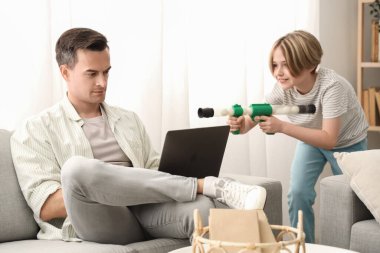 Dizüstü bilgisayarı olan genç bir adam evdeki yaramaz oğlundan dolayı stresli.