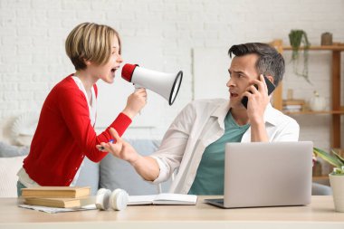 Çalışan genç adam, gürültücü küçük oğlunun evde megafona bağırmasından dolayı stresli.