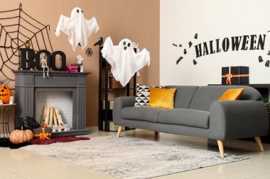 Cadılar Bayramı süslemeleri, gri kanepesi ve şöminesi olan festival salonu.