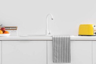 Lavabosu ve sarı tost makinesi olan beyaz mutfak tezgahları.