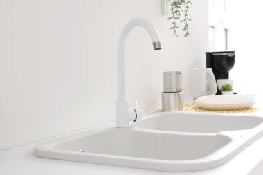 Beyaz mutfak tezgahında temiz lavabo, yakın plan.