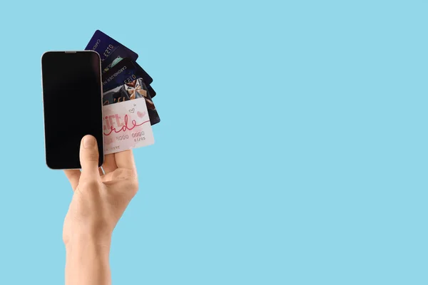 持空白手机和蓝色背景信用卡的妇女 — 图库照片