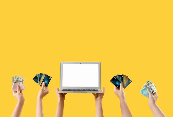 Women with blank laptop, money and credit cards on yellow background